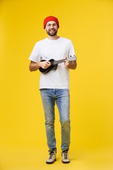 Guitarist man plays on the electric guitar with bright emotions, isolated on yellow background.