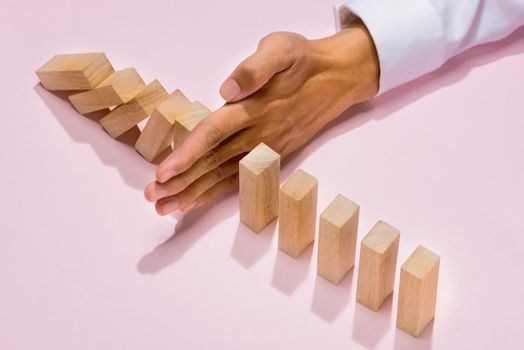 Hand of businessman stop dominoes continuous toppled
