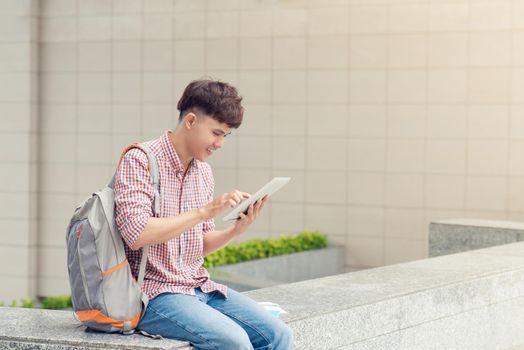 Male student using digital tablet in college campus