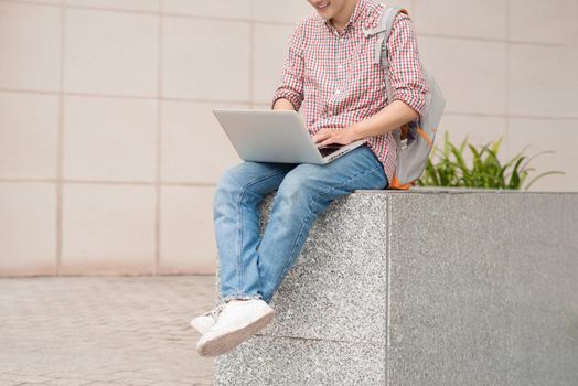 Male student using laptop in college campus