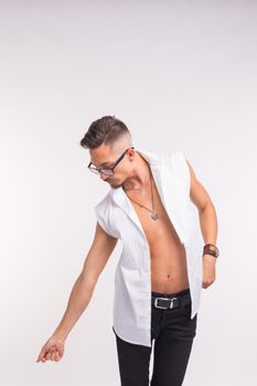 Fashion and people concept - handsome man in glasses and unbuttoned shirt looking down over the white background
