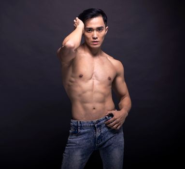 Muscular bodybuilder Asian man doing posing over black background