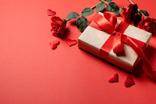 Valentines Day gifts, roses and confetti on red backdrop, copy space
