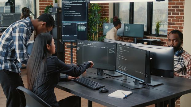 Mixed team of programmers analyzing source code pointing at screens comparing algorithm