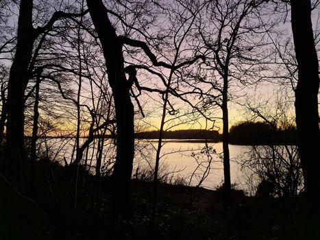 A lake at sunset with silhouettes of trees.
