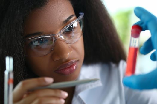 African american chemist holds glass test tube with red liquid solution