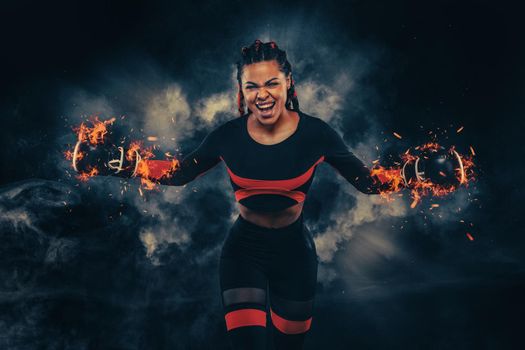 Boxing sport concept. Woman with braids on black background with smoke. Girl sportsman muay thai boxer fighting in gloves in gym.