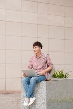 Male student using laptop in college campus