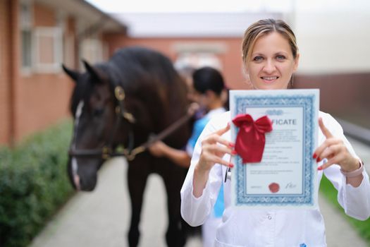Happy woman vet doctor holding a horse certificate