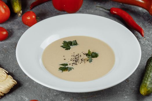 Cheese cream soup with sliced cheese and bread crumbs on a grey background