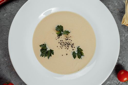 Cheese cream soup with sliced cheese and bread crumbs on a grey background