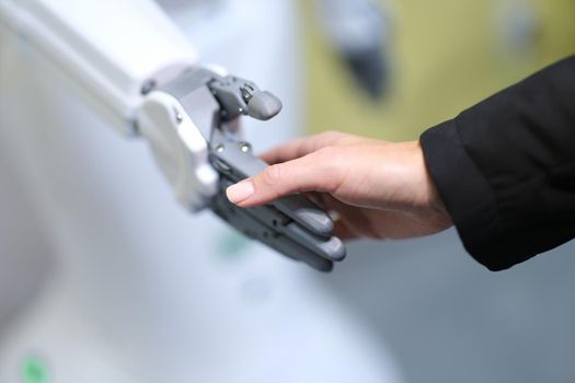Human and robot handshake, hands close-up, blurry. Human mechanical assistant. Tactile sensitivity, artificial intelligence