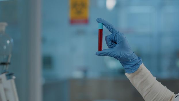Lab worker holding red substance in test tube for science analysis