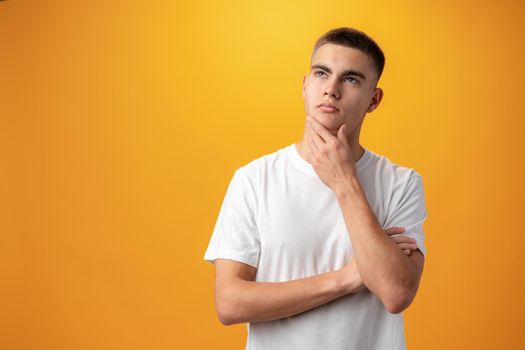 Young teen man thinking about things against yellow background