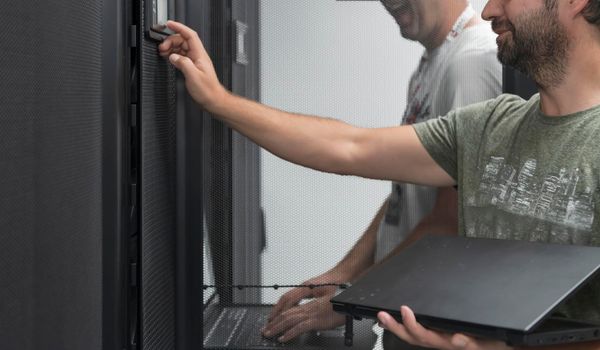 Technicians team updating hardware inspecting system performance in super computer server room or cryptocurrency mining farm.