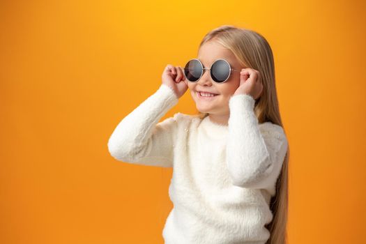 Little girl wearing sunglasses on a yellow background