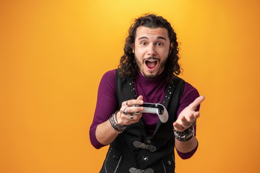 Photo of funny astonished guy with joystick playing video games over yellow background