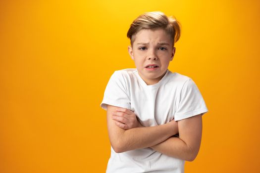 Unhappy teen boy being nervous, displeased with something over yellow background