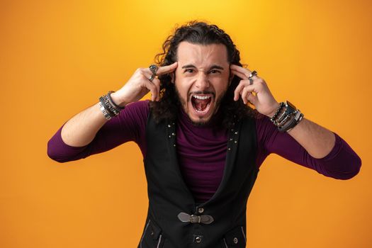 Angry young guy look in camera and scream against yellow background
