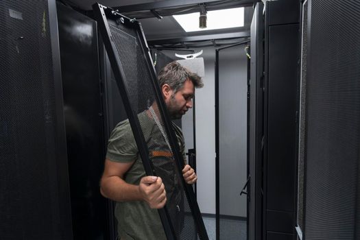 IT engineer working In the server room or data center The technician puts in a rack a new server of corporate business mainframe supercomputer or cryptocurrency mining farm.
