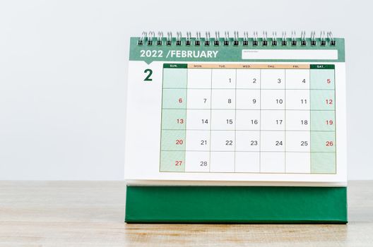 February 2022 desk calendar on wooden table.