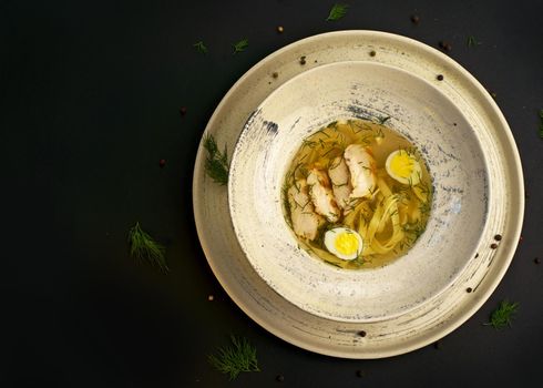 broth with noodles and quail egg in a white plate on a black background