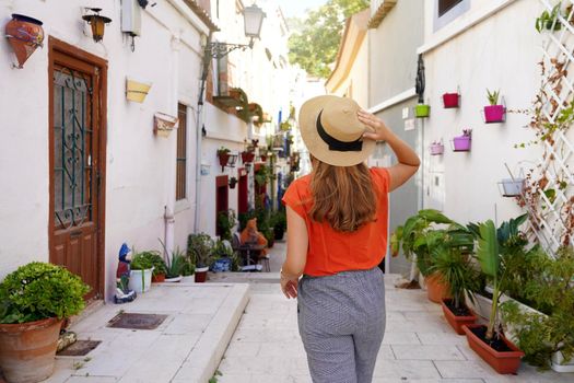 Visiting Alicante in Spain. Traveler woman visits the neighborhood Santa Cruz of Alicante in Spain. Tourist girl exploring european city with typical Mediterranean architecture and decoration.