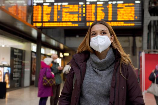 Traveler woman wearing medical face mask at the airport. Happy young woman walking and looking up with behind timetables of departures arrivals goes back to travel.