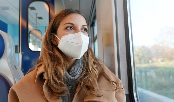 Travel safely on public transport. Panoramic banner of beautiful woman wearing FFP2 KN95 face mask on train looking through the window.