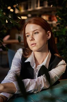 caucasian redhead pretty girl with long hair sitting at coffee shop table