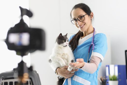Female doctor present cute kitty on camera, petting him for video