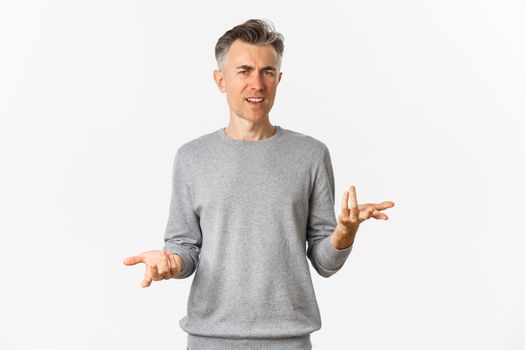 Portrait of confused and disappointed middle-aged man arguing, cant understand something and asking why, standing over white background perplexed