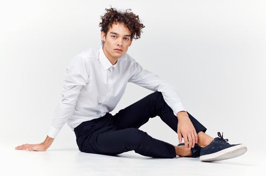 guy in a white shirt sitting on the floor curly hair fashion