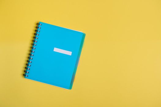 Flat lay of office supply, blue colourful organizer, notepad with empty blank sheet for text, isolated on yellow background with copy space.