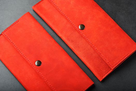 A pair of red genuine leather wallets with rivets on a dark background top view. Genuine leather