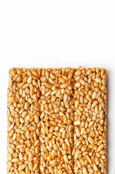 A large golden tile of sunflower seeds, a bar in a sweet molasses on a white background. Kozinaki useful and tasty sweets of the East