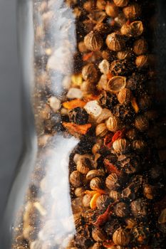 A mixture of seasonings, spices and herbs in a glass mill Close-up.
