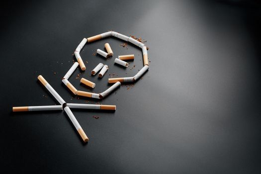 Skull from cigarettes on a black background. The concept of smoking kills. Toward the concept of smoking as a deadly habit, nicotine poisons, cancer from smoking, illness, quit smoking.