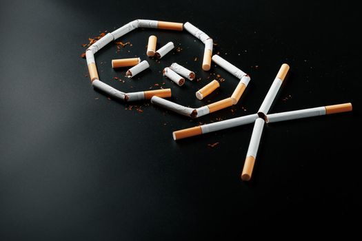 Skull from cigarettes on a black background. The concept of smoking kills. Toward the concept of smoking as a deadly habit, nicotine poisons, cancer from smoking, illness, quit smoking.