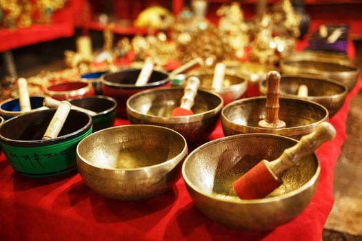 Golden Tibetan singing bowls on counters with red cloth of the night market