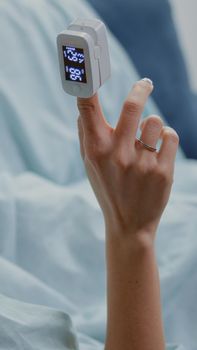 Close up of unwell woman holding oximeter on finger