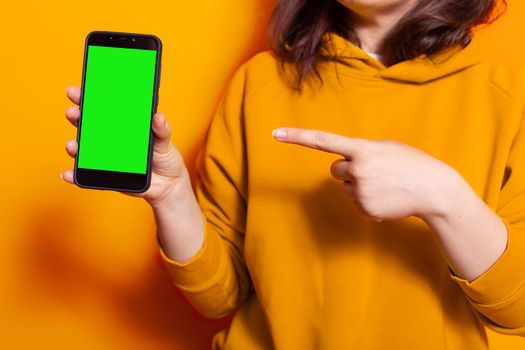 Close up of woman pointing at vertical green screen on phone