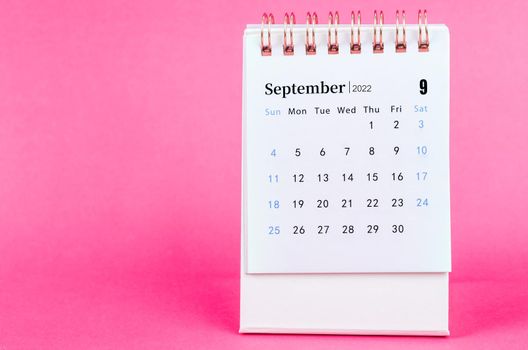 September 2022 desk calendar on pink background.