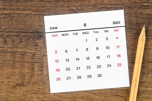 June 2022 calendar and wooden pencil on vintage wooden background.