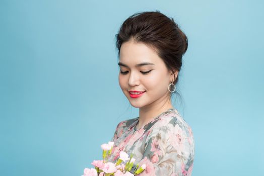 Portrait of charming Asia woman with flower bouquet over blue background