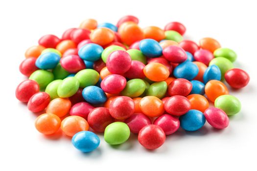 A rainbow of colors from multicolored candies close-up, multi-colored glaze dragee on a white background isolated