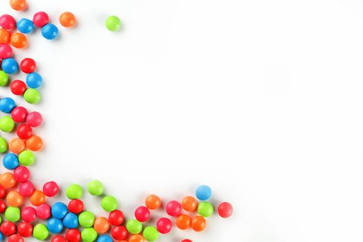 A rainbow of color from multicolored candies close-up, multi-colored glaze dragee on a white background