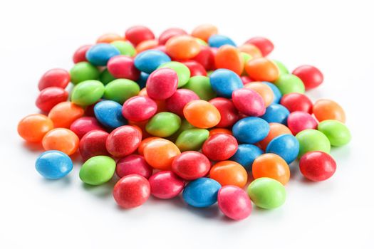 A rainbow of colors from multicolored candies close-up, multi-colored glaze dragee on a white background isolated