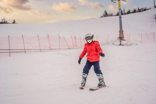 Child skiing in mountains. Active toddler kid with safety helmet, goggles and poles. Ski race for young children. Winter sport for family. Kids ski lesson in alpine school. Little skier racing in snow