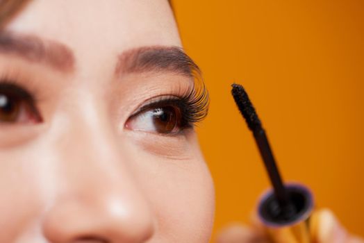 Beautiful woman applying mascara on her eyelashes 